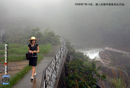 2008年7月13日,广东增城白水寨风景名胜区,一名游客在雨中游览白水天池。