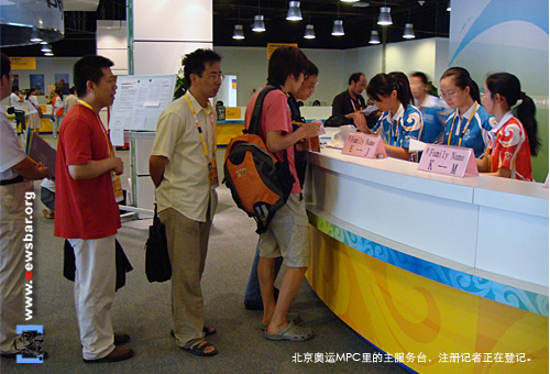 北京奥运MPC里,为记者服务的人们——MPC主服务台的志愿者正在为注册记者进行登记。